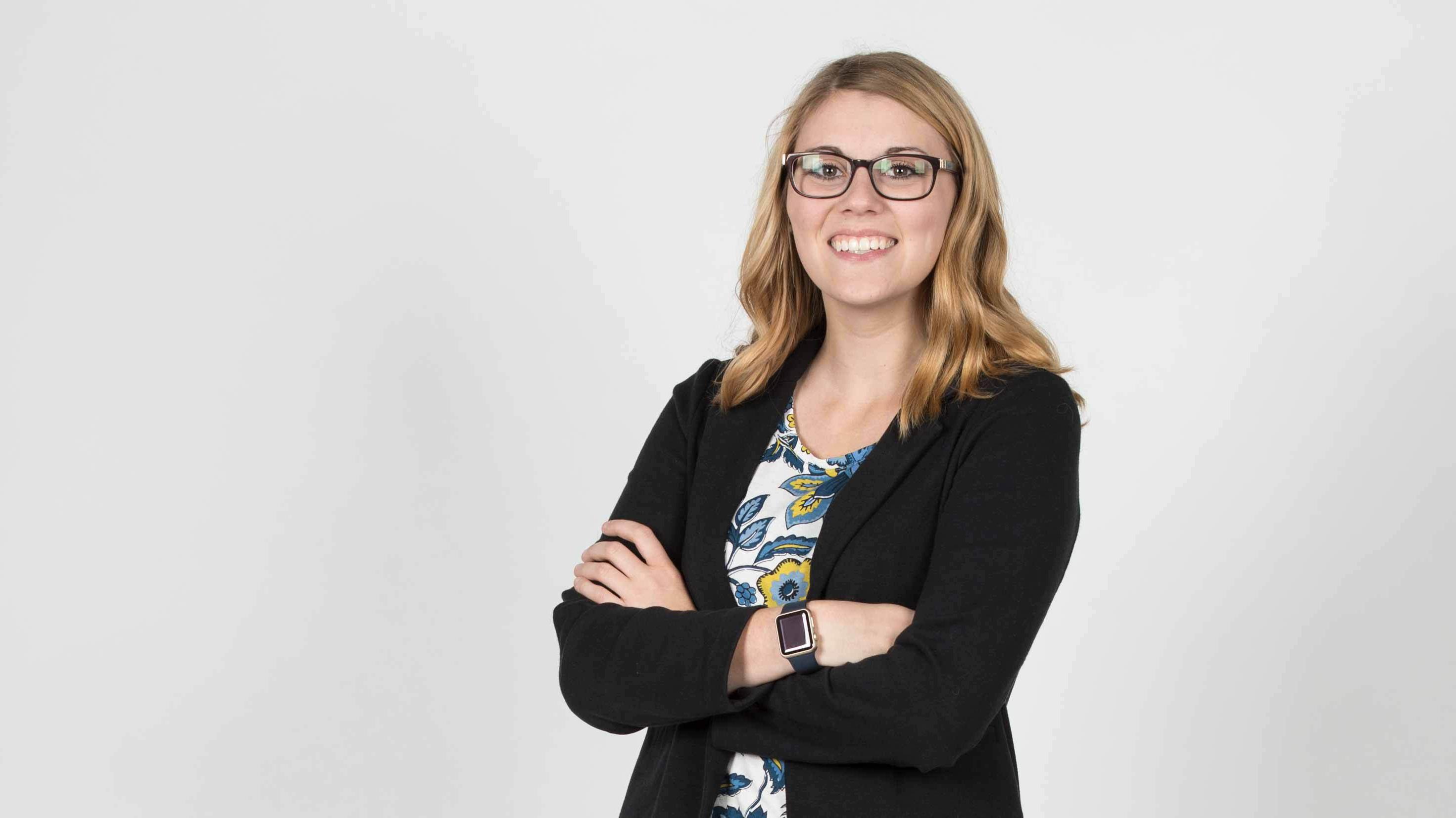 Smiling woman with glasses standing with arms crossed